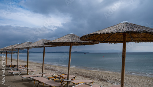 Straw umbrellas and beach chairs on a sandy beach.