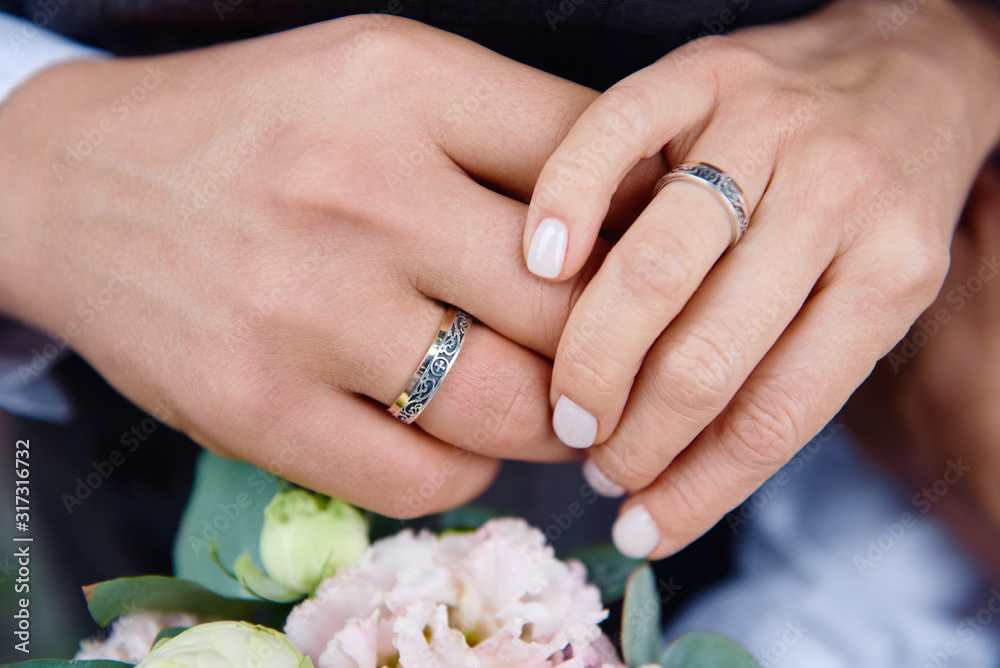 Newlywed couple's hands with wedding rings on bridal bouquet, copy space. Wedding couple, bride and groom, hands with rings, closeup Newlywed couple's hands with wedding rings on bridal bouquet, copy space. Wedding couple, bride and groom, hands with rings, closeup