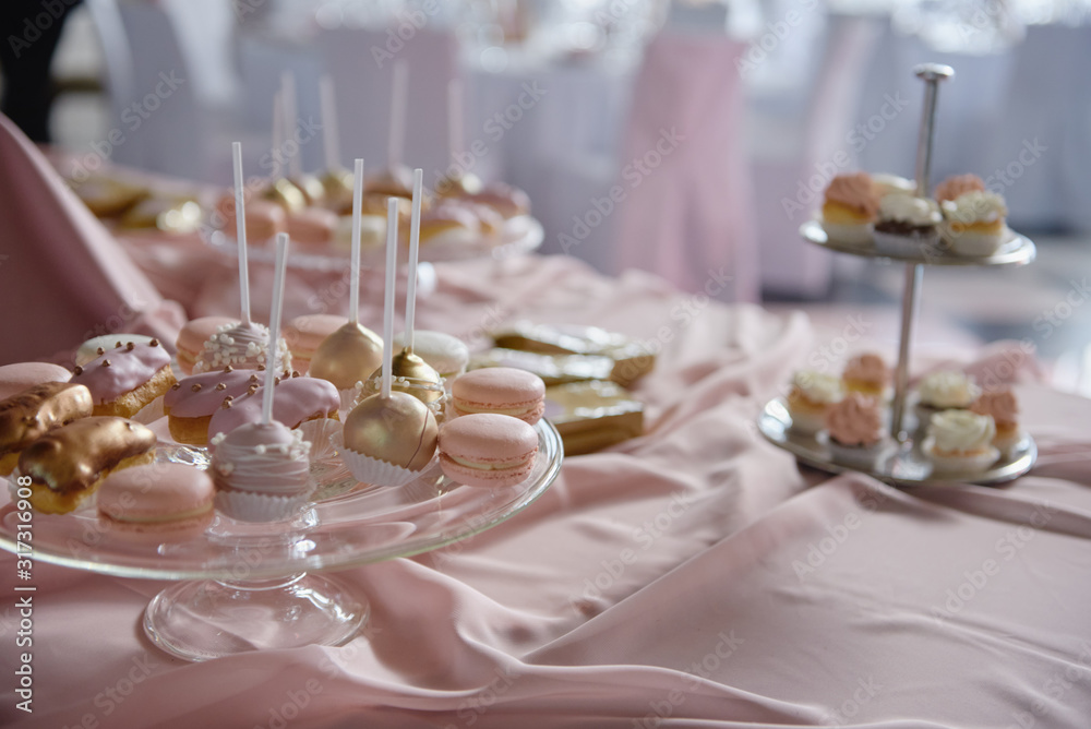 Naklejka premium Candy bar served with macaroons, choux pastry and cake pops in restaurant, copy space. Dessert table for party pink color. Holiday concept