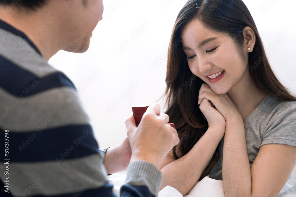 Valentine's Day, Asian couple is spending time together in home, Man surprising his girlfriend with a gift. Valentine's Day, Asian couple is spending time together in home, Man surprising his girlfriend with a gift.