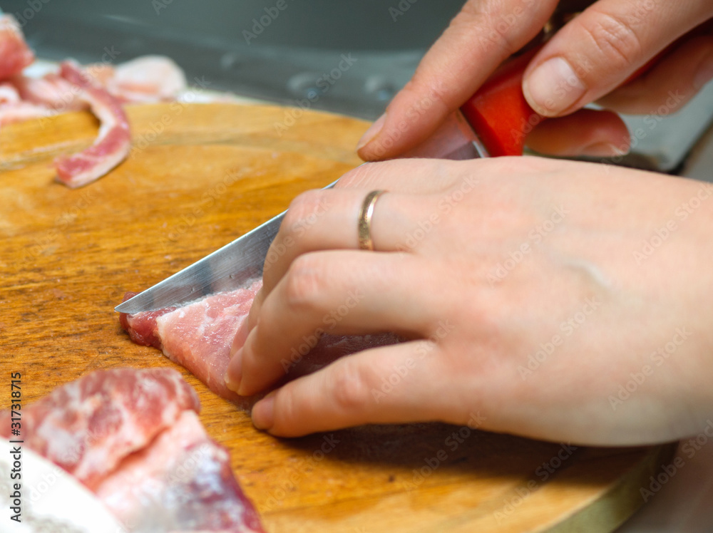 girl cuts meat on a wooden Board