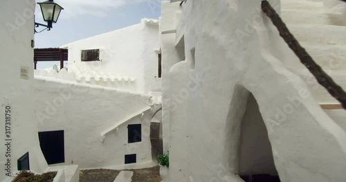 Binibeca old fishing village in Minorca, Balearic Islands, Spain. Walking for very narrow streets of the traditional Mediterranean architecture. Wide angle view with personal perspective camera move.  photo