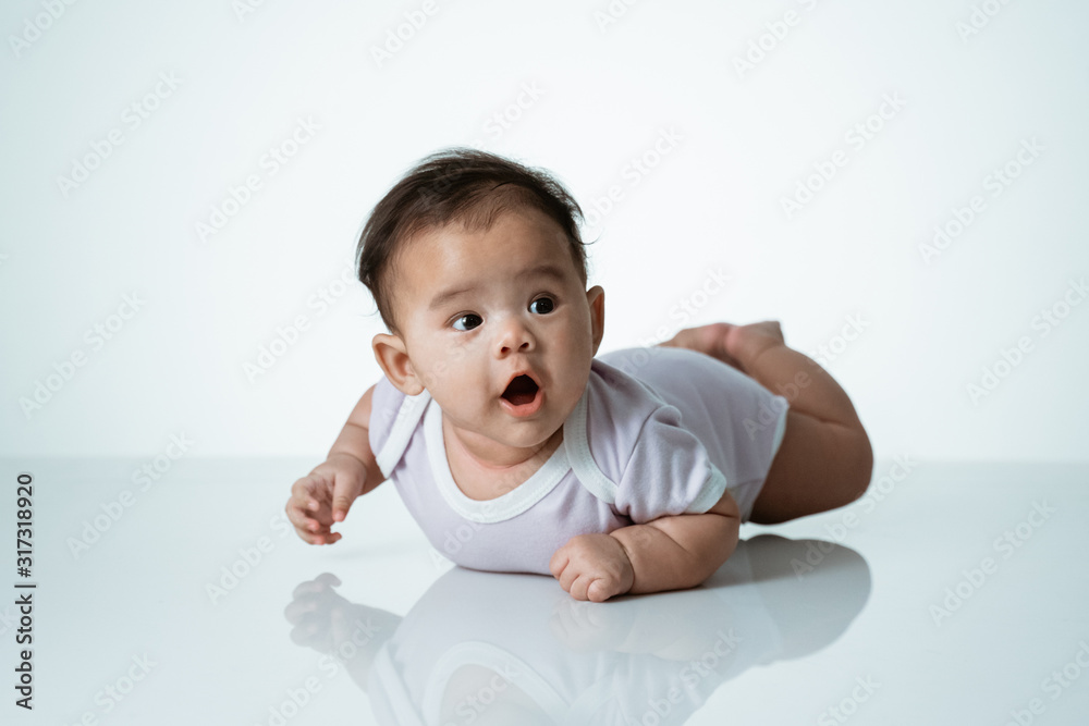 baby laying on her belly. tummy time cute baby in studio portrait on white background baby laying on her belly. tummy time cute baby in studio portrait on white background