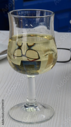 Die Spiegelung einer Brille in einem Glas Weißwein