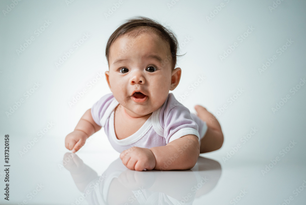 baby laying on her belly. tummy time cute baby in studio portrait on white background baby laying on her belly. tummy time cute baby in studio portrait on white background