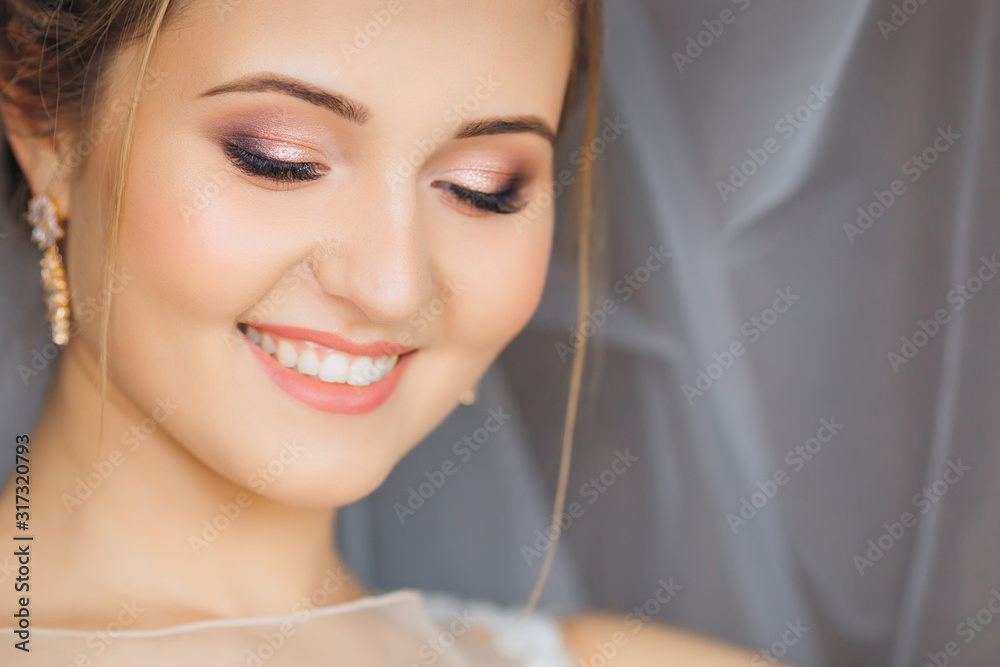 chic bride in gentle makeup look down and smile. wedding veil in