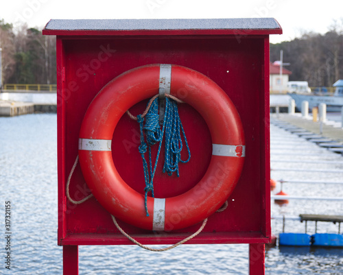 Red lifebuoy with a blue rope to save people at the sea, lake, river