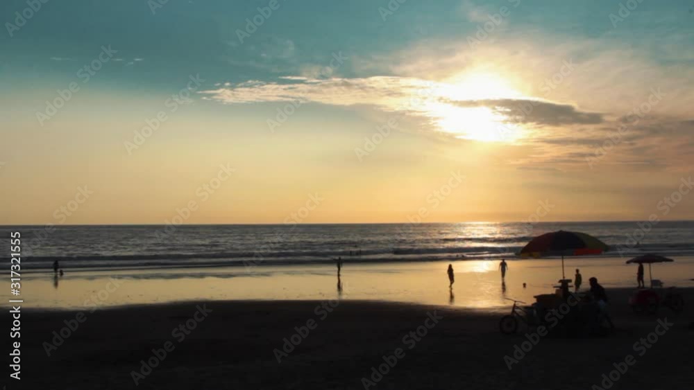 People enjoying the beach in Montanita, Ecuador at sunset in silhouette with ocean in the background People enjoying the beach in Montanita, Ecuador at sunset in silhouette with ocean in the background