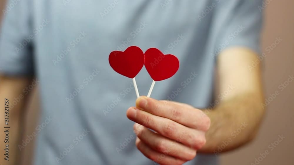 Valentine's Day. Guy hold two hearts in his hands. Brings hearts closer. copyspace Valentine's Day. Guy hold two hearts in his hands. Brings hearts closer. copyspace