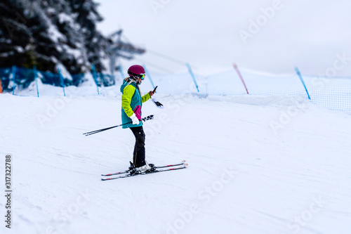 Far view of woman checking smartphone during ski