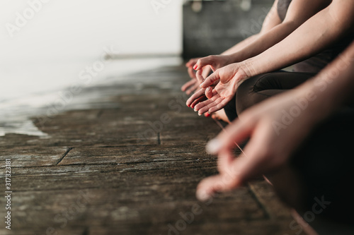 hands of women meditating outdoors near sea sitting on yoga mat
