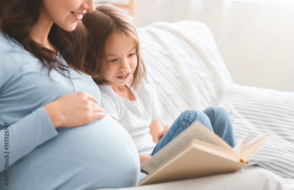 Close up of excited little girl reading book with mom Close up of excited little girl reading book with mom
