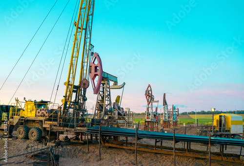 Workover rig working on a previously drilled well trying to restore production through repair. The pumping units and well workover operation photo