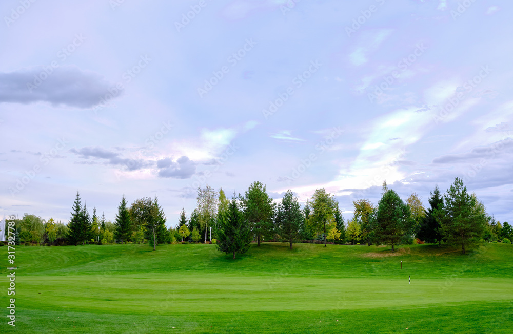 View of the golf course with green lawn trees and ornamental shrubs. Golf course, beautiful scenery.