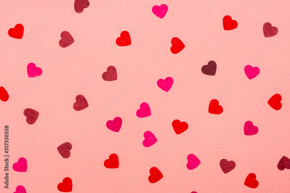 Valentines Day background. Pattern of paper confetti in shape of heart different colors on pink background. Festive composition. Flat lay, top view