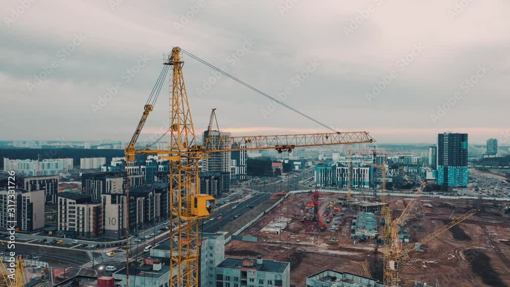 City residential block near construction site. Construction machinery is building apartment residential area. Yellow cranes for building an apartment panel house or block of flats. City residential block near construction site. Construction machinery is building apartment residential area. Yellow cranes for building an apartment panel house or block of flats.
