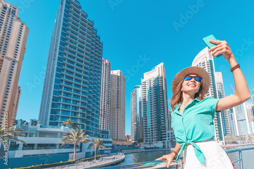 Photography Happy asian girl taking selfie photo on a smartphone while walking on a promenade in Dubai Marina district