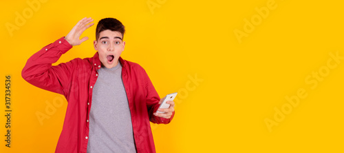 amazed young teenager boy looking at mobile phone with surprise isolated on color background photo