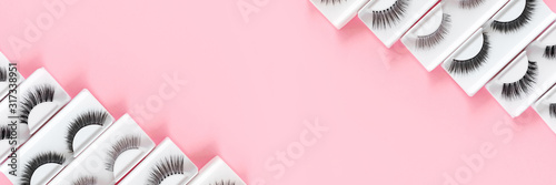 Different fake eyelashes on a trendy pastel pink background. Beauty pattern. Makeup accessories. Cosmetics products for women. Top view  flat lay. Layout. Copy space. Place for text and design. Banner