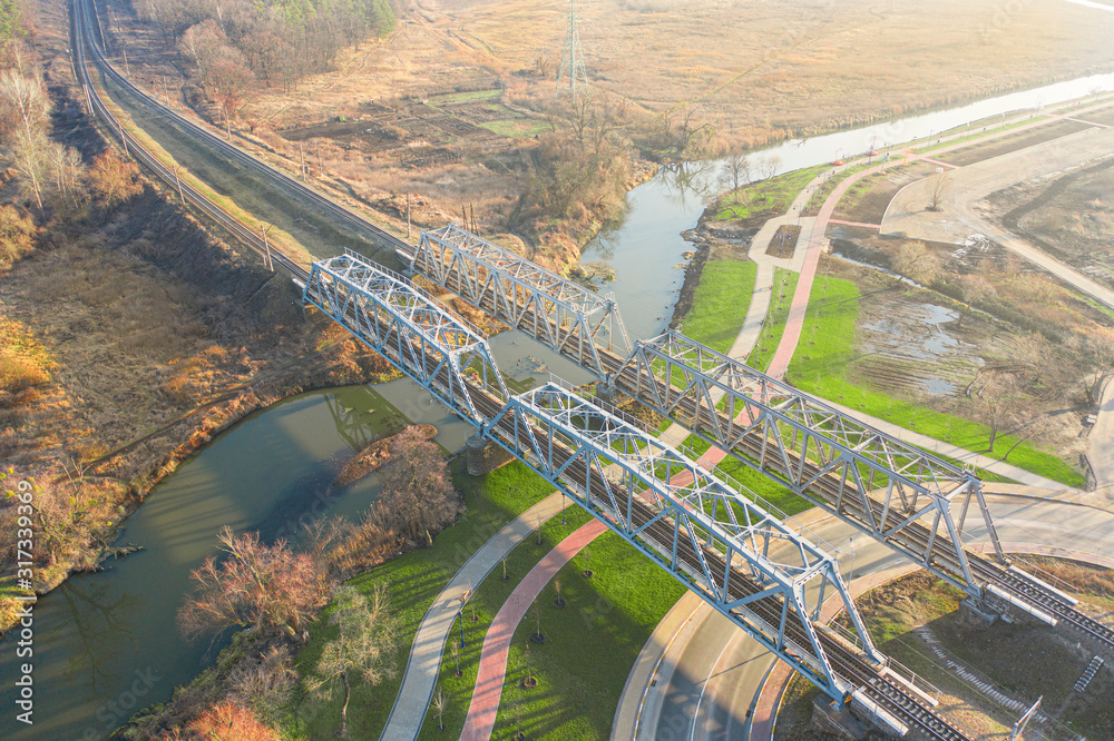 Two metal railway bridges over a small river, view from the drone.