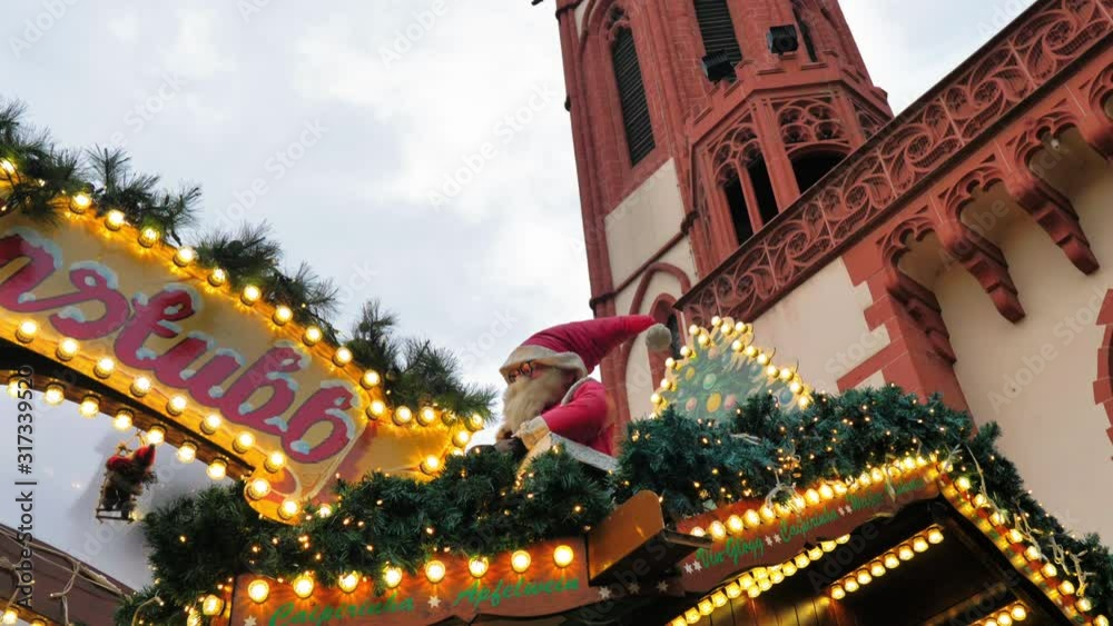 Muñeco de Papa Noel junto a luces navideñas y campanario de iglesia