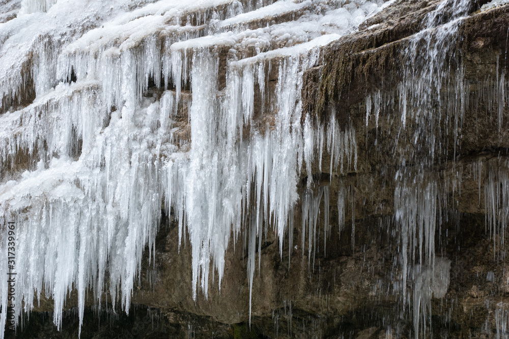 icicles from the jets of a frozen waterfall on a brown rock. winter in caucasian mountains icicles from the jets of a frozen waterfall on a brown rock. winter in caucasian mountains
