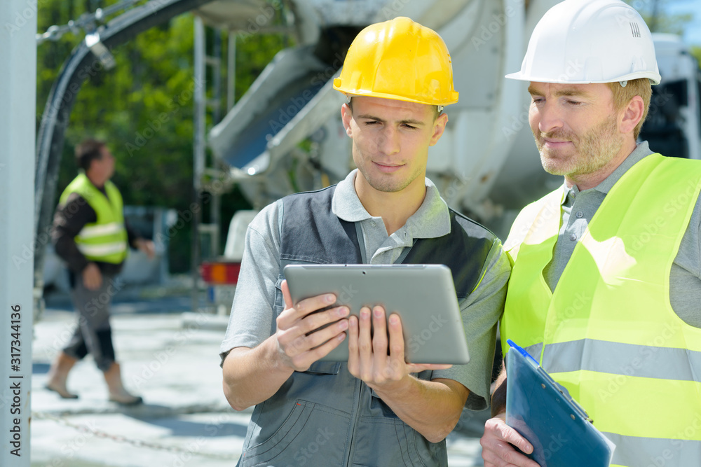 workers on outdoor site looking at tablet workers on outdoor site looking at tablet