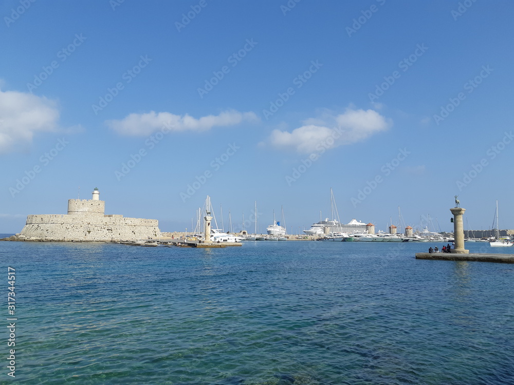 Harbor of Rhodes, GREECE , Old Venetian watch tower at old seaport of Rhodes island.ancient port.Lighthouse and Fortress Bastion of St. Nicholas at Old seaport.deer statue at Mandraki harbor