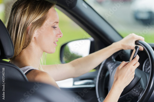 woman checking her phone while driving © auremar