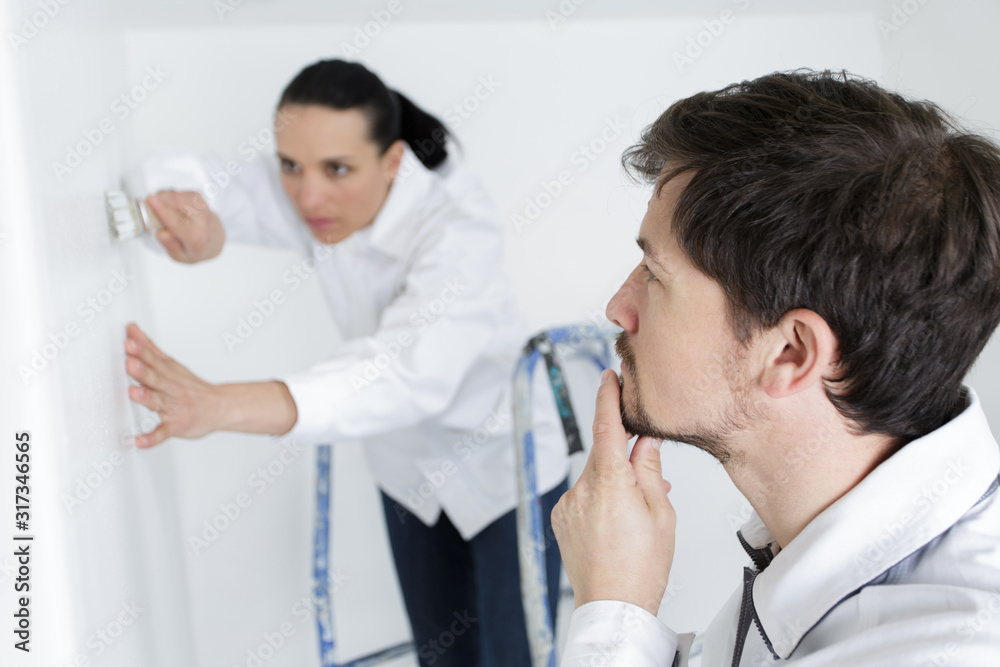Obraz premium foreman watching woman paint an interior wall