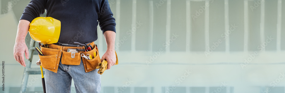 Contractor With Toolbelt and Hard Hat In Front of Drywall Banner Contractor With Toolbelt and Hard Hat In Front of Drywall Banner