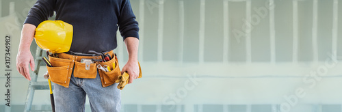 Contractor With Toolbelt and Hard Hat In Front of Drywall Banner © Andy Dean