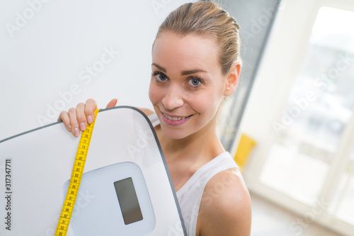 woman holding weighing scale with measuring tape