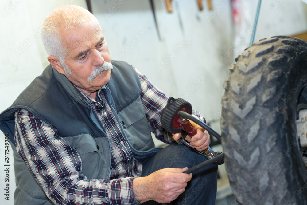senior mechanic changing a wheel of a modern car senior mechanic changing a wheel of a modern car