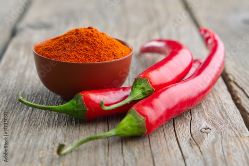 Whole and ground to powder red chili pepper on wooden kitchen table. photo