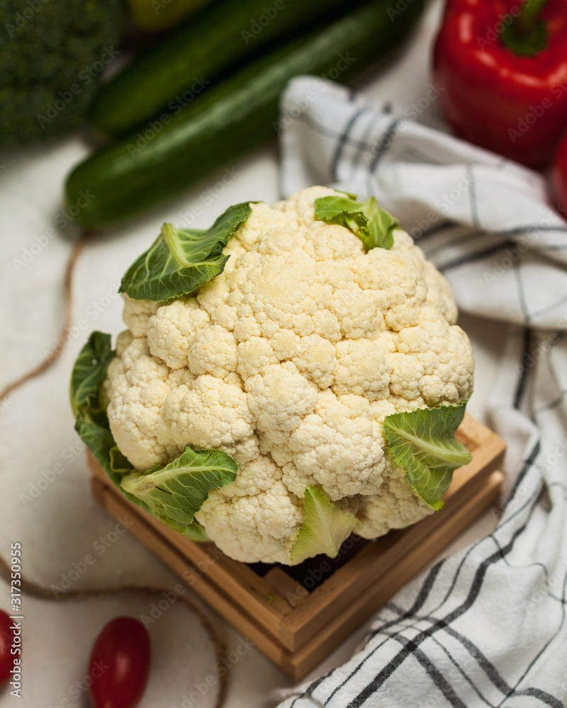 Fresh cauliflower closeup on a wooden stand, in the background cucumbers, broccoli, peppers, tomatoes. Fresh cauliflower closeup on a wooden stand, in the background cucumbers, broccoli, peppers, tomatoes.