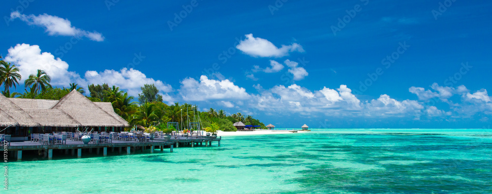 Beach with white sand, turquoise ocean water and blue sky with clouds in sunny day. Natural background for summer vacation. Panoramic view.