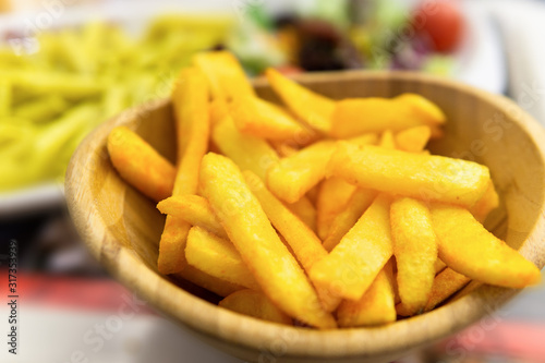 french fries with spice sauce in wooden bowl