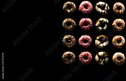 abstract black background of colored donuts with space for your text, sweet dessert