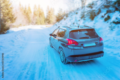 Car drives through the snowy mountain. Rear view of car and road. Concept of safe driving with winter tires