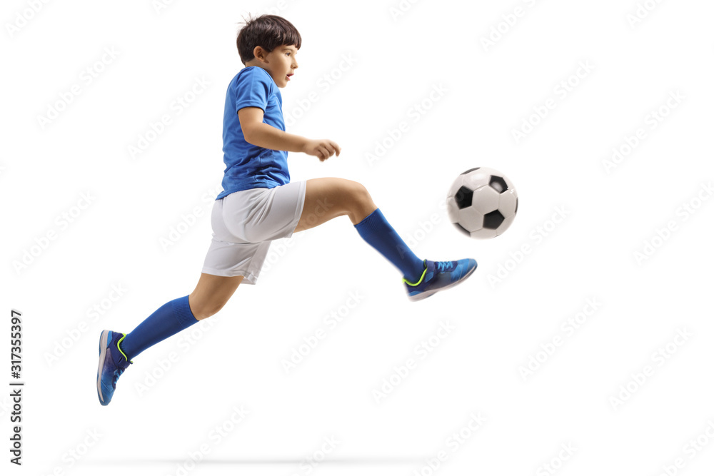 Boy jumping and kicking a soccer ball