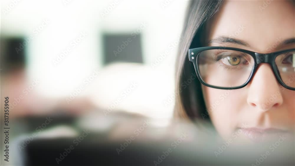  Attractive young woman working in a touchscreen computer or tablet. Businesswoman with glasses in an office space. Technology. Daylight. Dolly shot. 