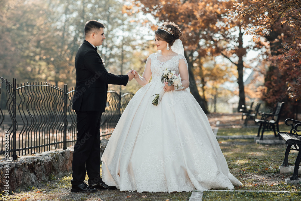Sunshine portrait of happy bride and groom outdoor in nature location at sunset. Warm summertime. Happy couple with a beautiful bouquet of flowers. Wedding photo. Couple in love. Autumn wedding Sunshine portrait of happy bride and groom outdoor in nature location at sunset. Warm summertime. Happy couple with a beautiful bouquet of flowers. Wedding photo. Couple in love. Autumn wedding