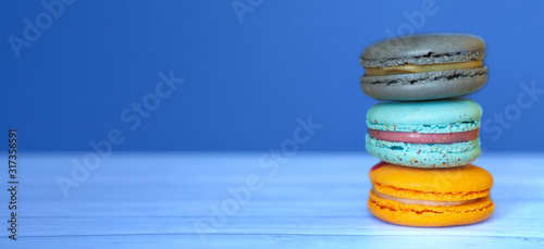 Fototapeta Naklejka Na Ścianę i Meble -  Colored macaroons on blue classic background, french cookies as a treat for the holiday, space for text