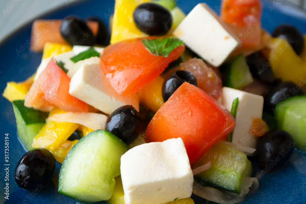 Close up of fresh greek salad on blue bright plate Close up of fresh greek salad on blue bright plate