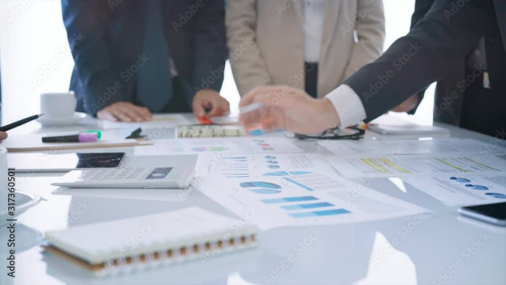 Diverse group of executives having a business meeting. They are discussing over financial data and graphs, showing the development of their company. 