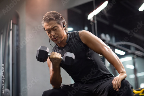 Mature man working out with hand weights at gym