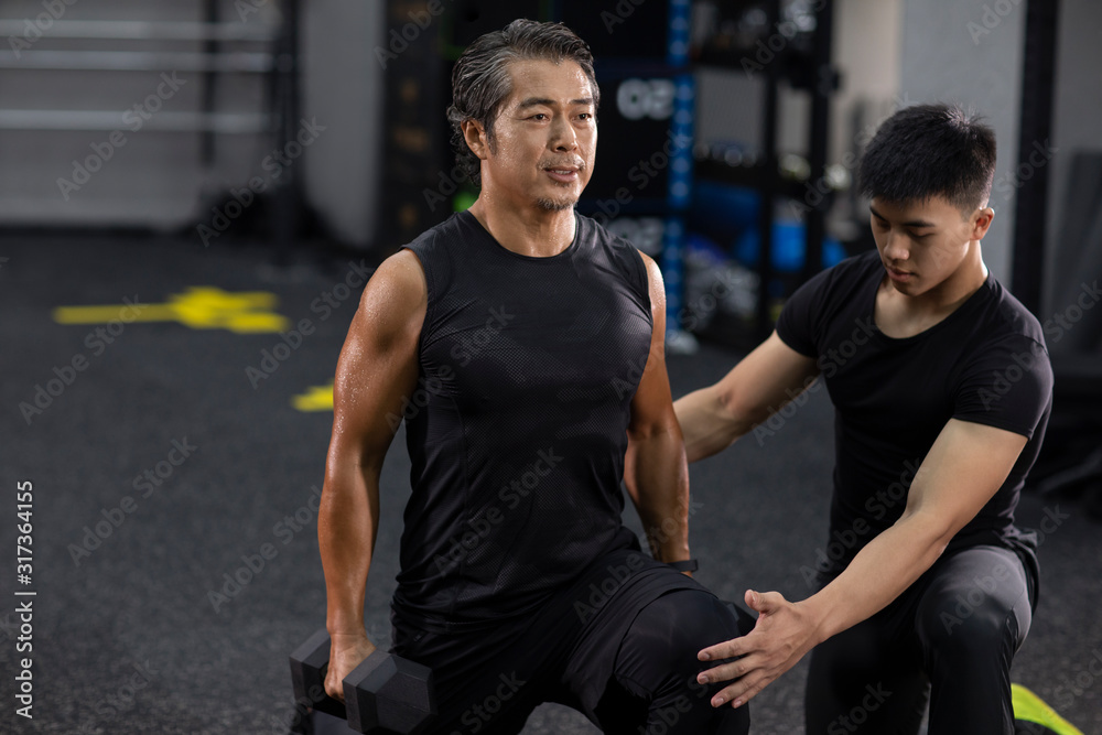 Mature man working out with personal trainer at gym Mature man working out with personal trainer at gym
