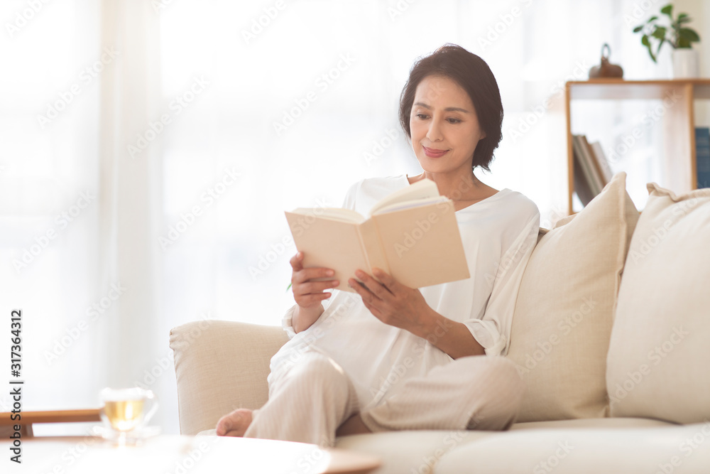 Mature woman reading book on sofa Mature woman reading book on sofa