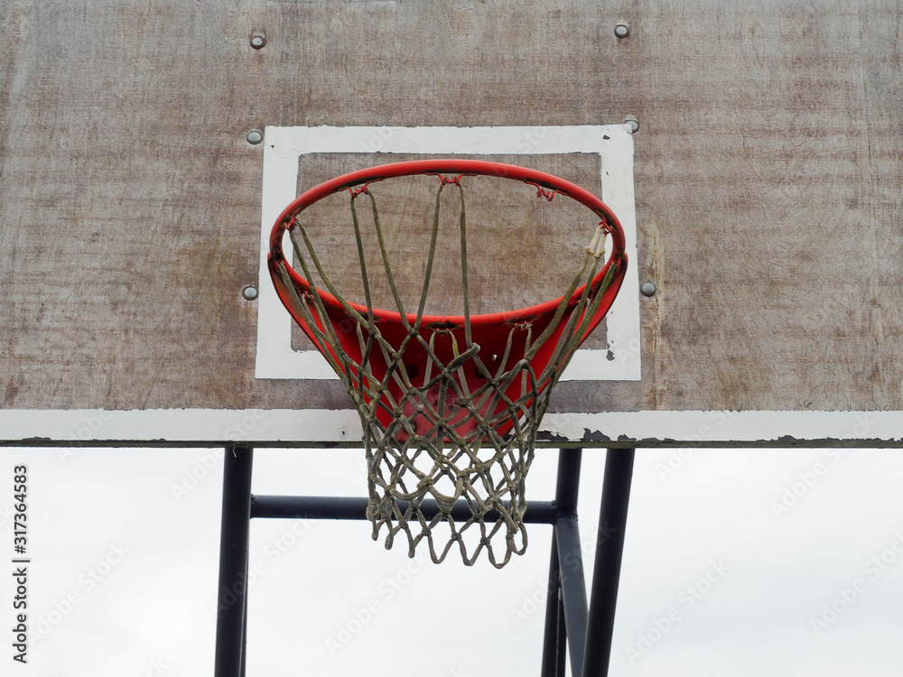 Basketball red hoop and net on a wooden old worn board,